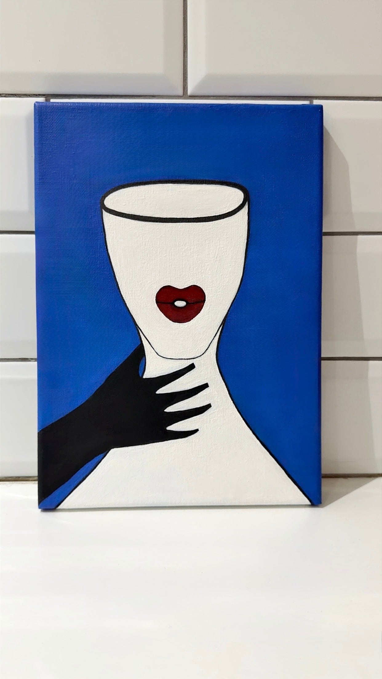 Surreal artwork of a hand holding a cup with a red heart on a blue background